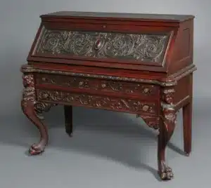 “Ornate writing desk restored with carved detailing and polished finish”