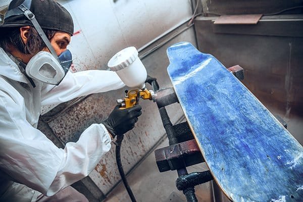 Restoration team applying spray -finish to vintage cabinet—First Class MasterCraft precision and care