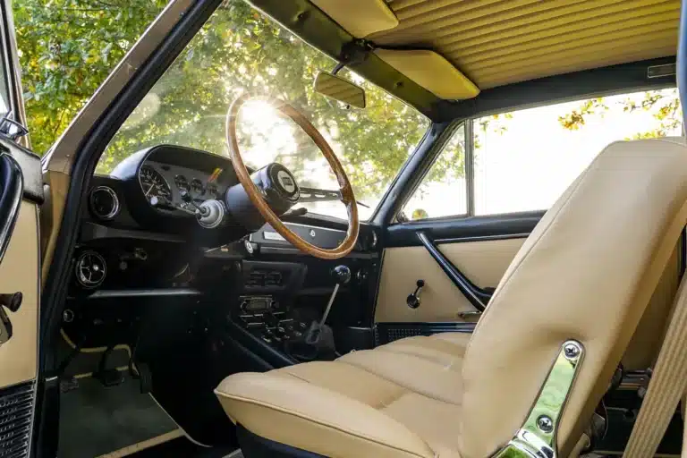 “Restored muscle car cabin—red leather seats and black dashboard detailing”