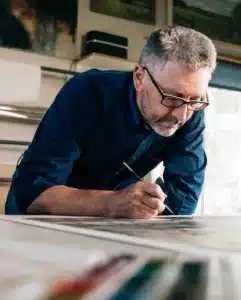 “First Class MasterCraft team member at desk – coordinating upholstery and cabinetry projects in Fort Lee workshop”