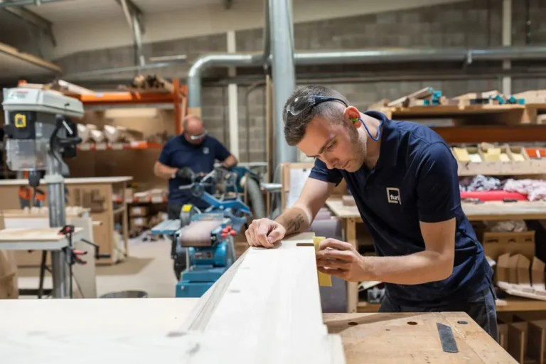 Team member shaping wood components for cabinetry – First Class MasterCraft precision millwork