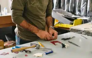 team member working on the bench repairing tiny leather